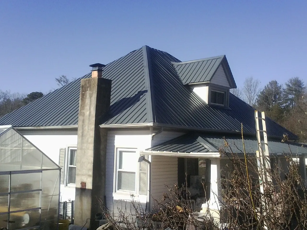 Dark blue standing seam metal roof on a white farmhouse with dormer — Slate & Tile Roof Repair by Roofing Brothers in Corbett