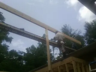 Carpenter setting a ridge beam over a new addition frame — Ice Dam Removal by Roofing Brothers in Corbett