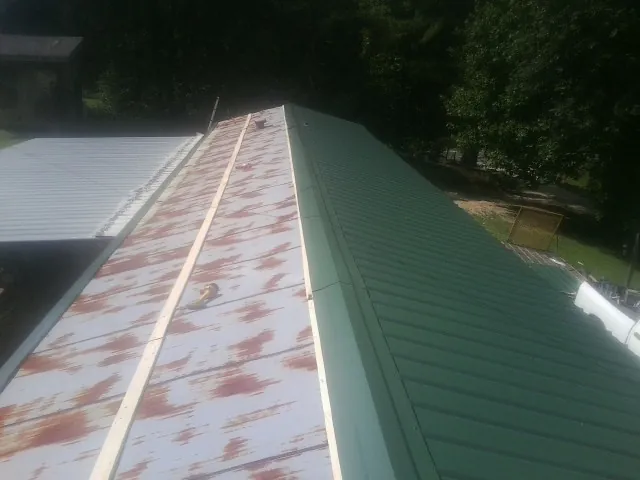 Old rusted panels beside newly installed green metal roofing — Wind Damage Roof Repair by Roofing Brothers in Corbett