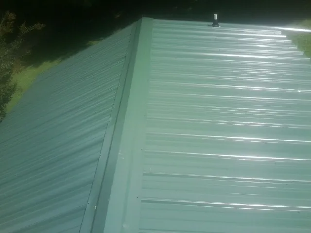 New green metal panels meeting at the ridge of a roof — Flat Roof Repair work by our crew in Corbett