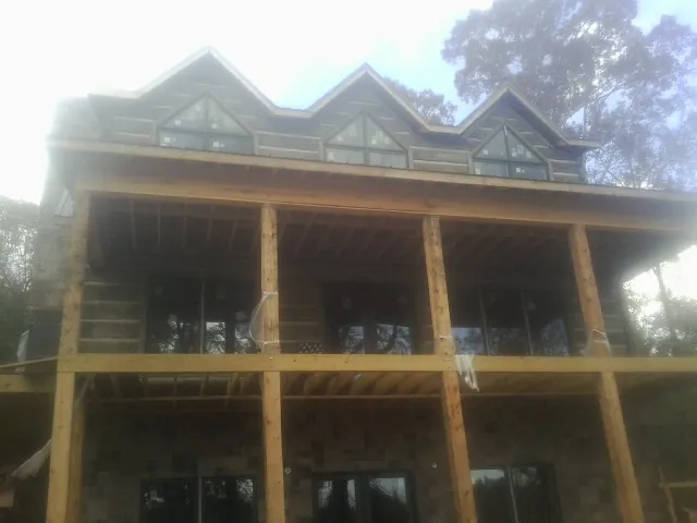 Dormers and porch framing on a large log home under construction — Roof Coating work by our crew in Corbett