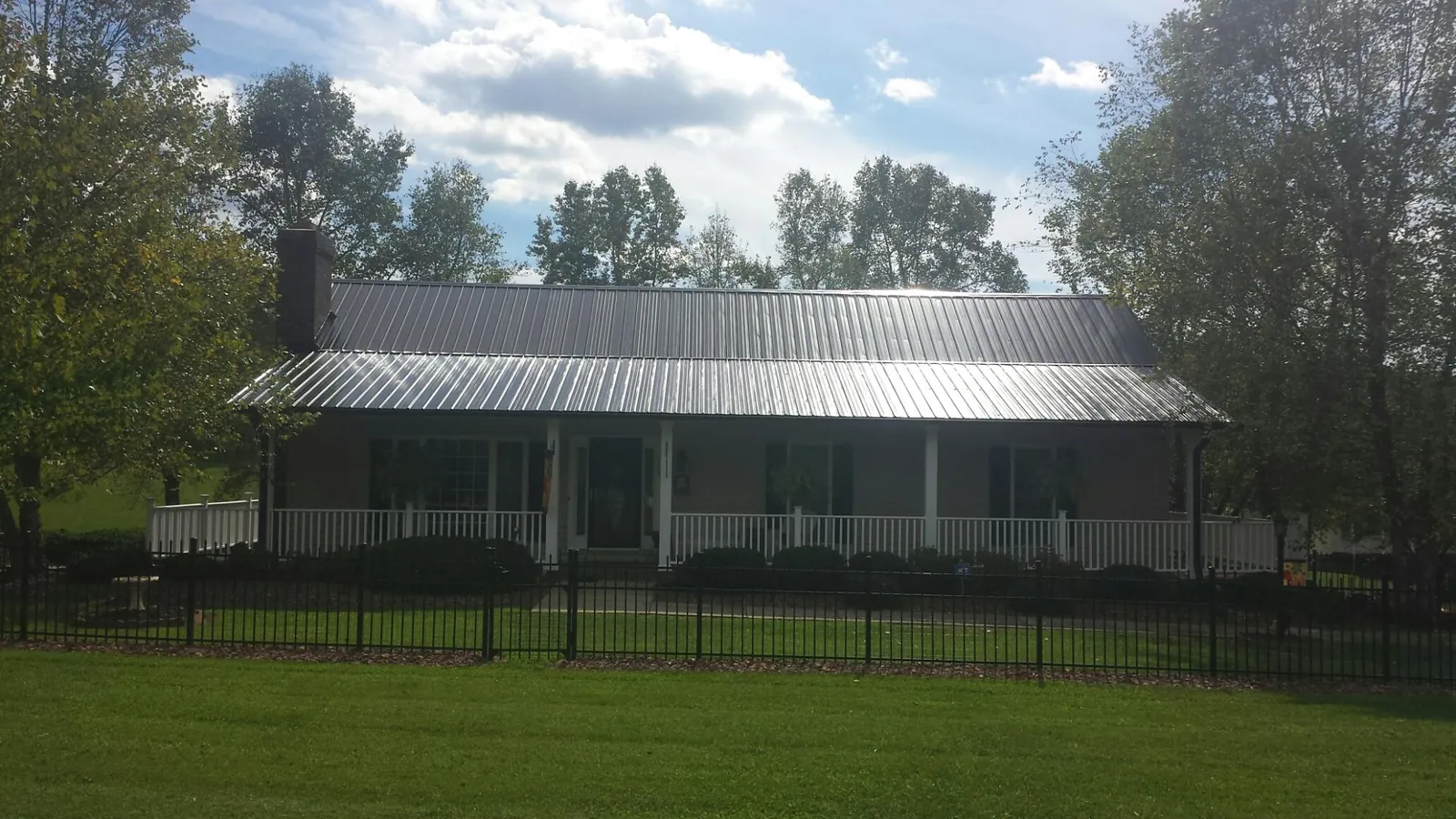 Gray metal roof on a brick ranch with a full width front porch — Gutter Guard Installation work by our crew in Corbett