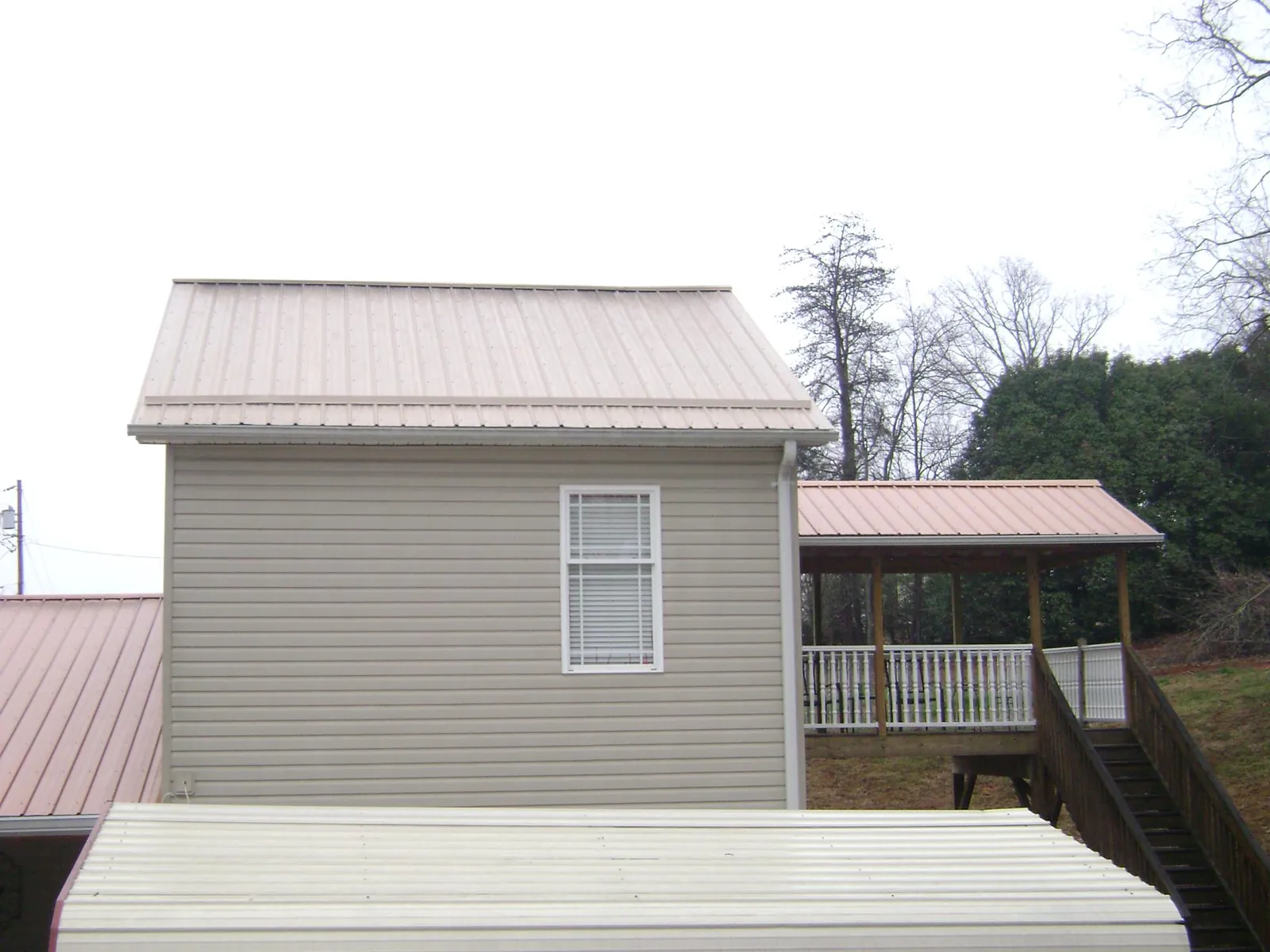Tan metal roofs on a two story addition and attached porch, from a Roof Replacement job in Corbett