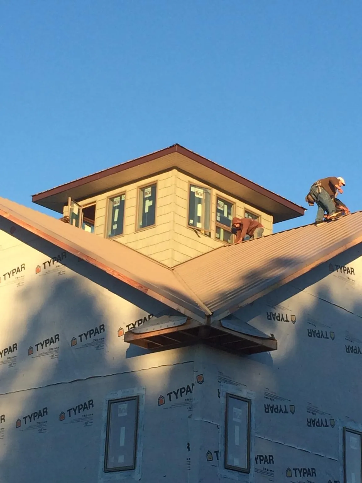 Roofers working around a rooftop cupola on a new metal roof at sunset — Roof Waterproofing in Corbett by Roofing Brothers